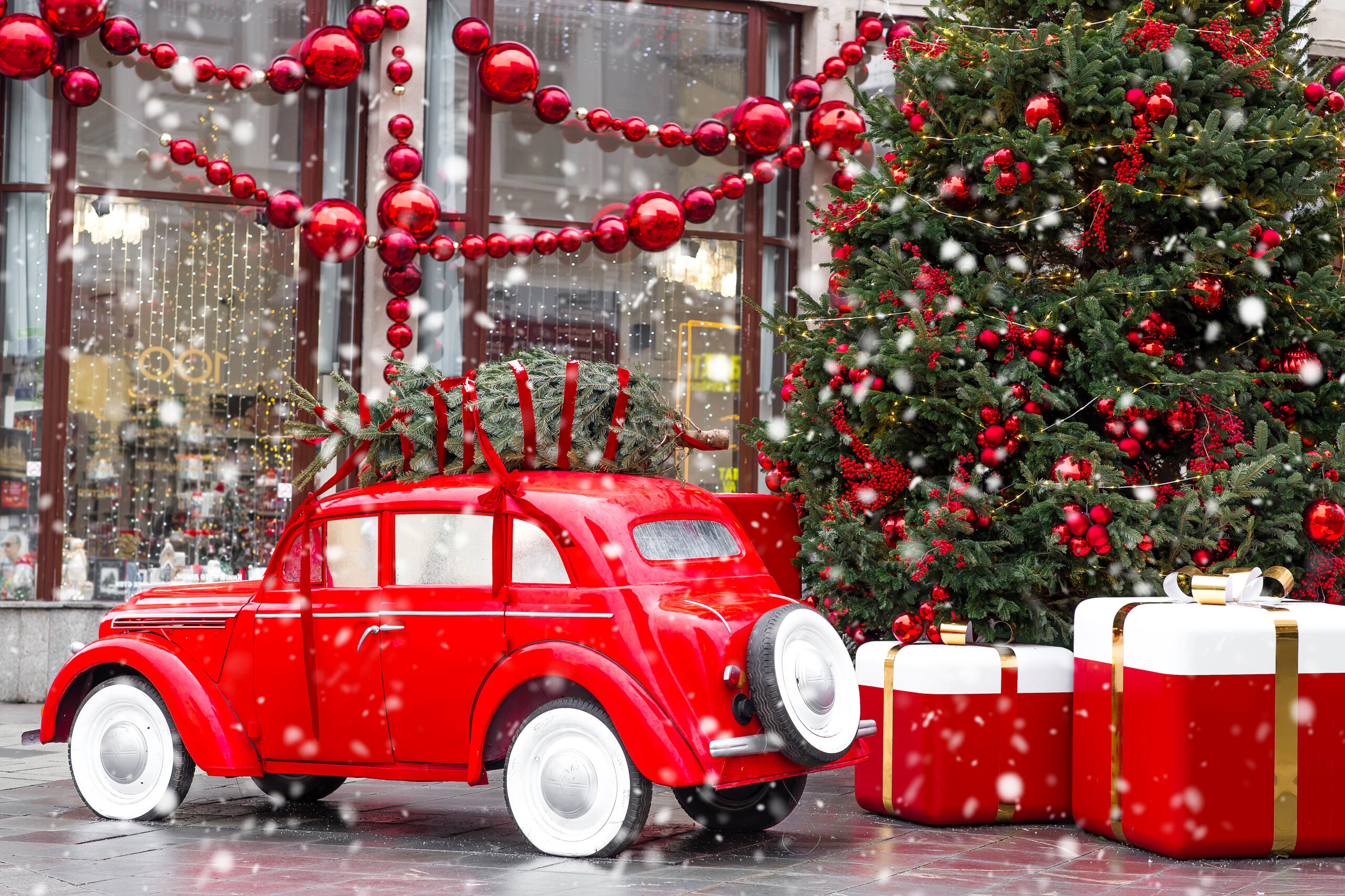 Product Delivery Concept. A Vintage Red Christmas Car Is Carrying A Christmas Tree On Its Roof. Decorated New Year's Moscow.