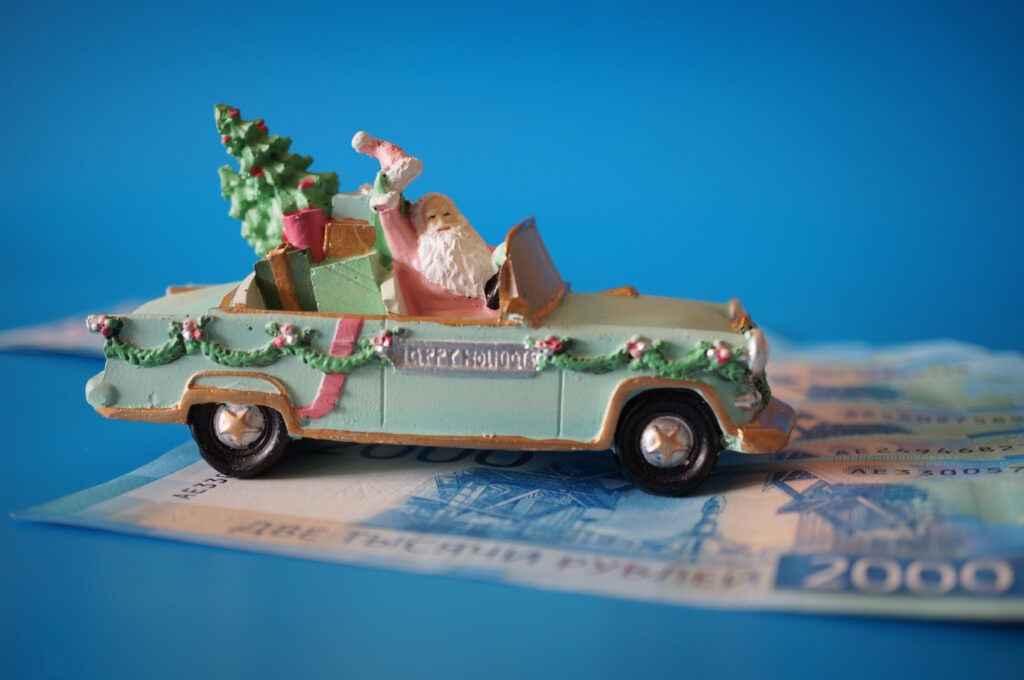 A Toy Car With Santa And Money On A Blue Background.