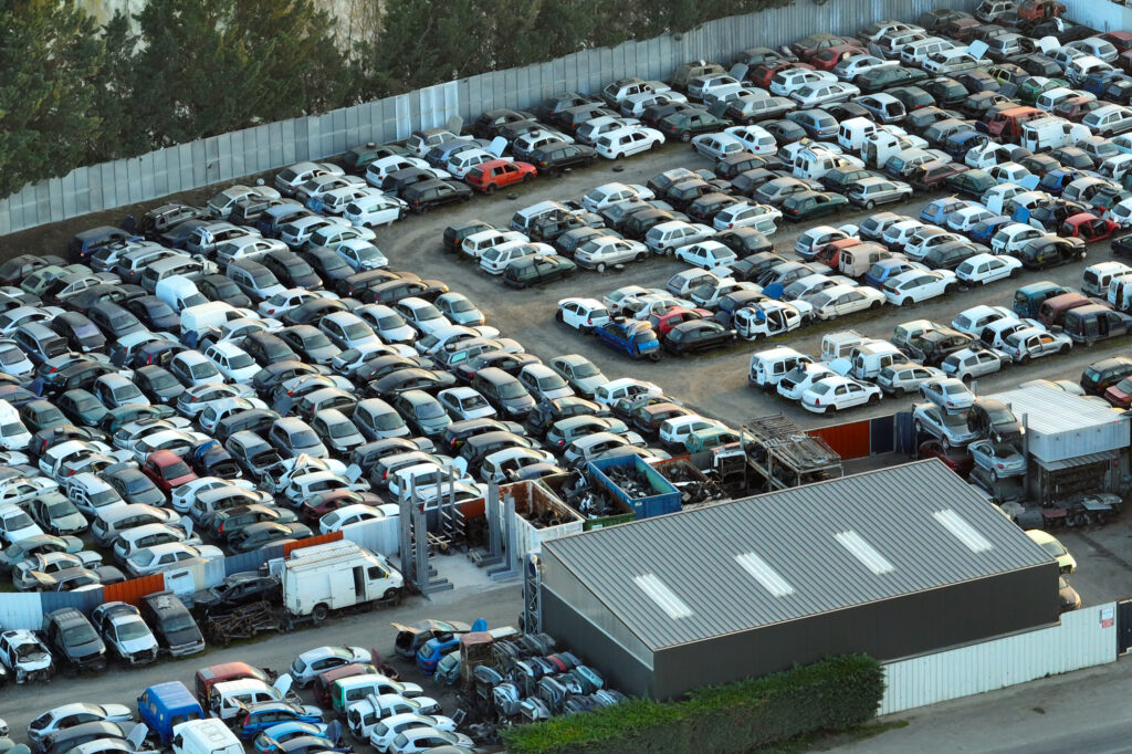 Aerial View Of Big Parking Lot Of Junkyard With Rows Of Discarded Broken Cars. Recycling Of Old Vehicles