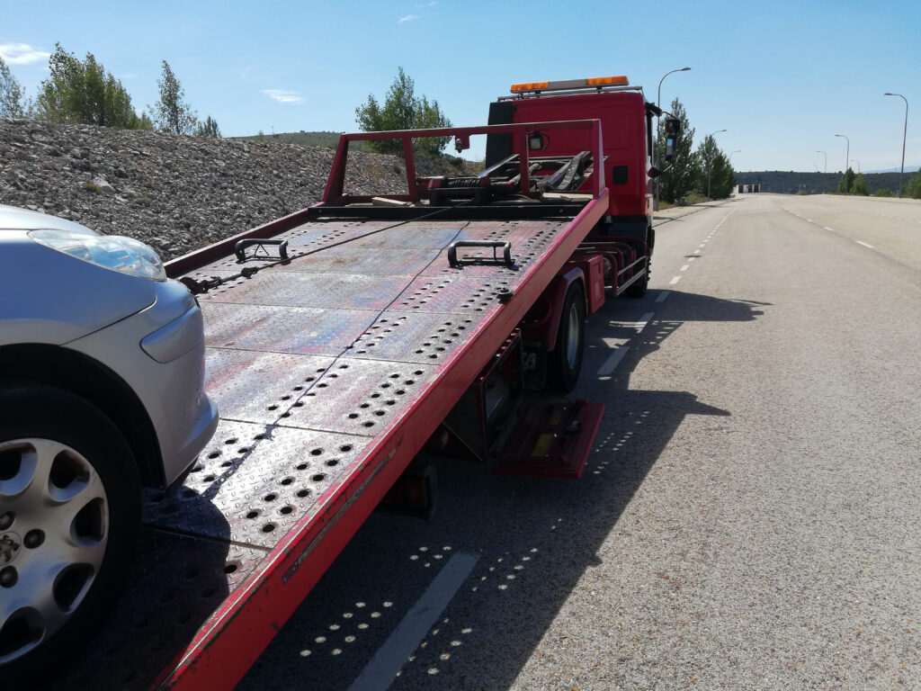 Detail Of A Tow Truck Towing A Damaged Car In The Middle Of The Street