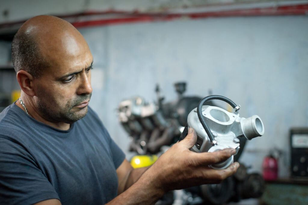 Mechanic Carefully Inspecting The Turbocharger.